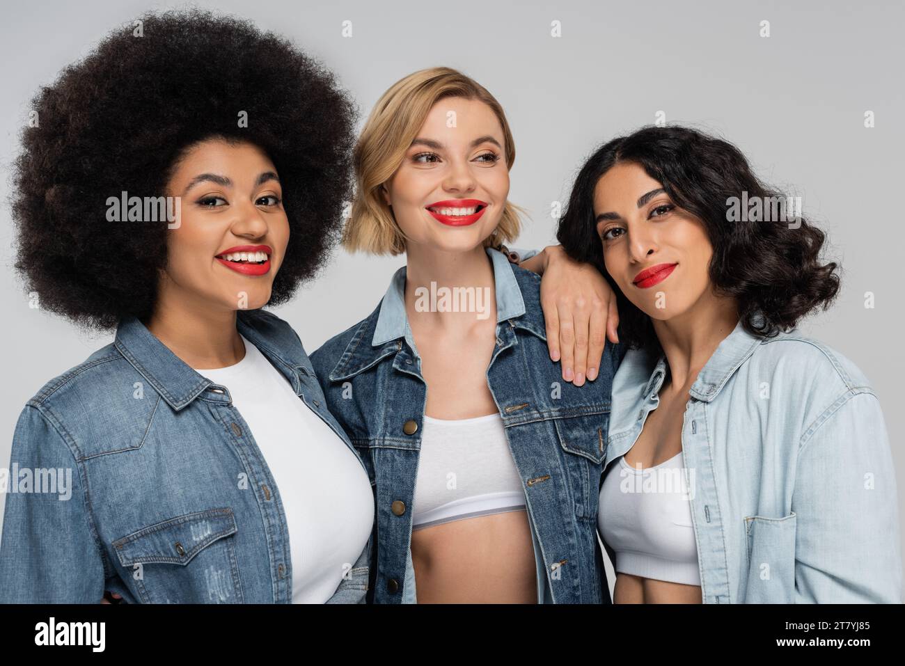 positif multiculturel divers modèles dans des tenues en denim bleu souriant sur le gris, l'amitié et la mode Banque D'Images