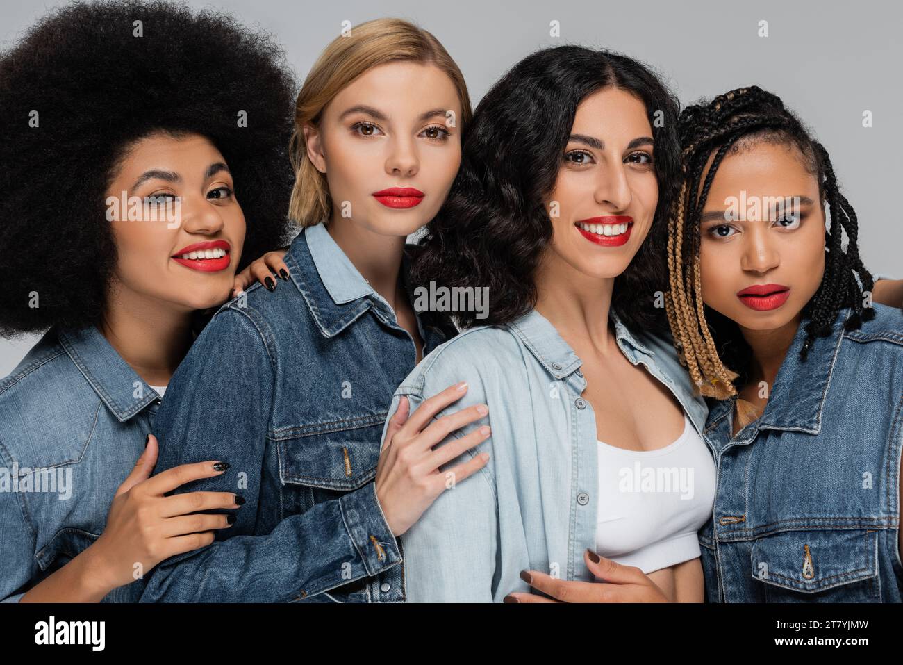 portrait de groupe de copines multiethniques en vêtements denim regardant la caméra sur gris, beauté diverse Banque D'Images