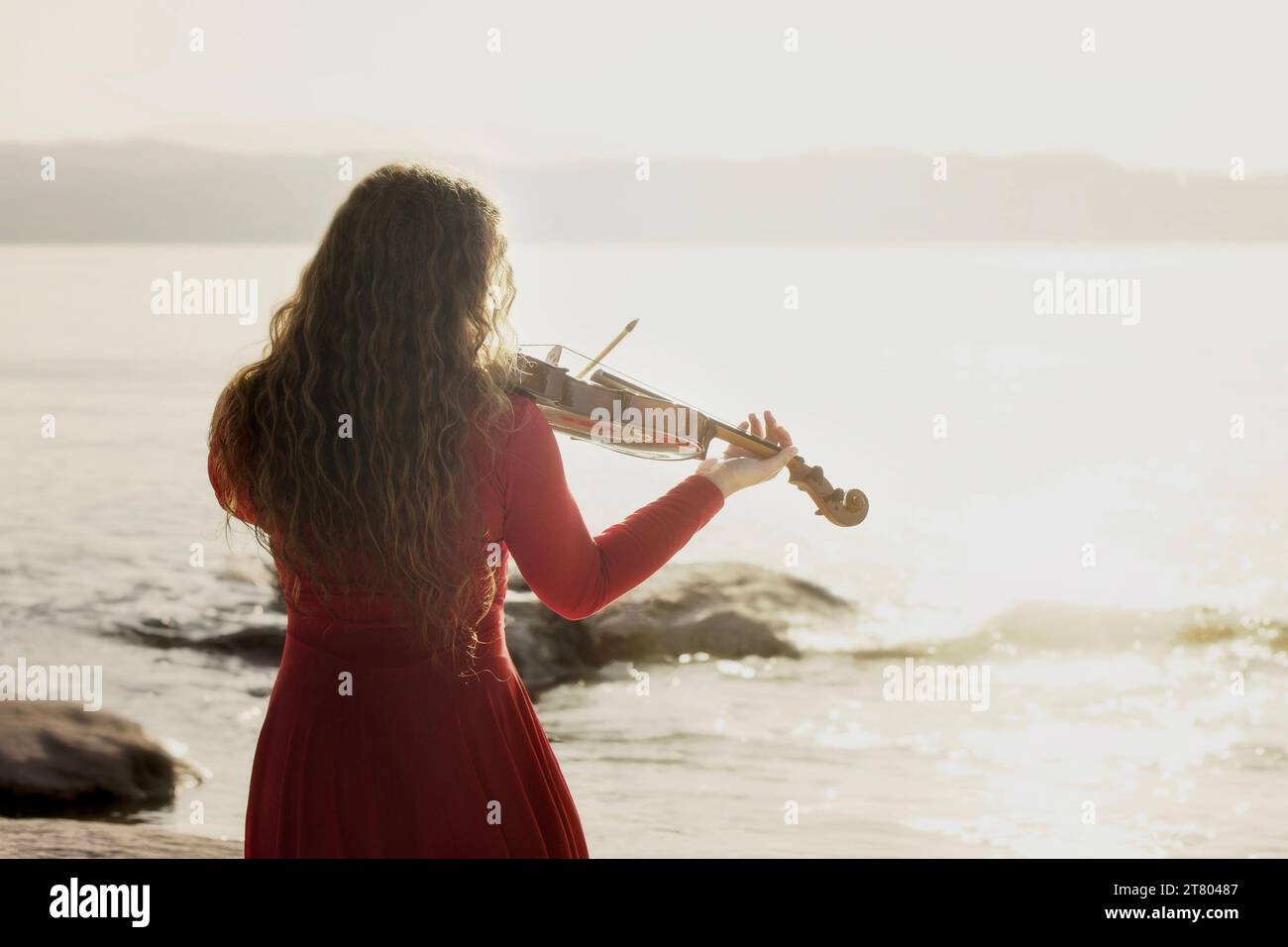 scène romantique d'une femme jouant du violon devant la mer Banque D'Images