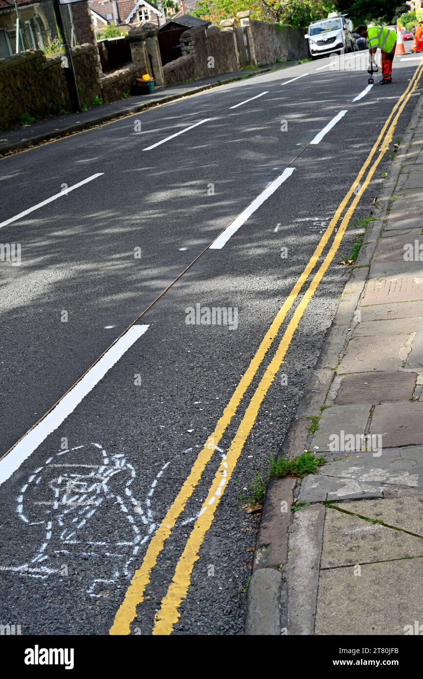 Workman peignant une ligne blanche avec de la peinture fondue chaude et du marquage au pochoir de piste de cycle prêt pour la peinture, Bristol, Royaume-Uni Banque D'Images