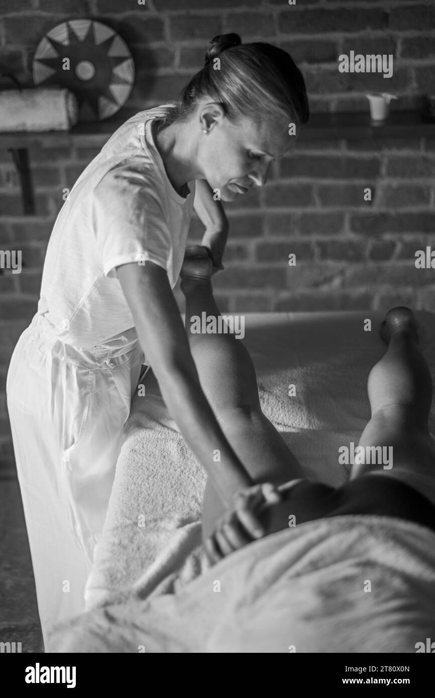 masseuse physiothérapeute féminine caucasienne professionnelle effectuant un massage de jambe à la femme hispanique latino-brunette dans la clinique de spa Banque D'Images
