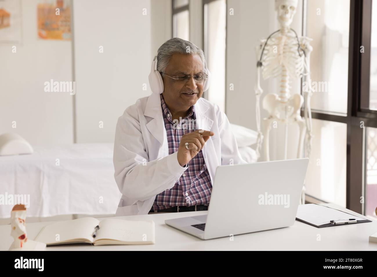 Homme médecin indien mature positif parlant sur appel vidéo Banque D'Images