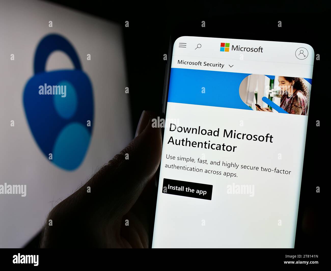 Personne tenant le téléphone portable avec la page Web de l'application d'authentification Microsoft Authenticator devant le logo de l'entreprise. Concentrez-vous sur le centre de l'écran du téléphone. Banque D'Images