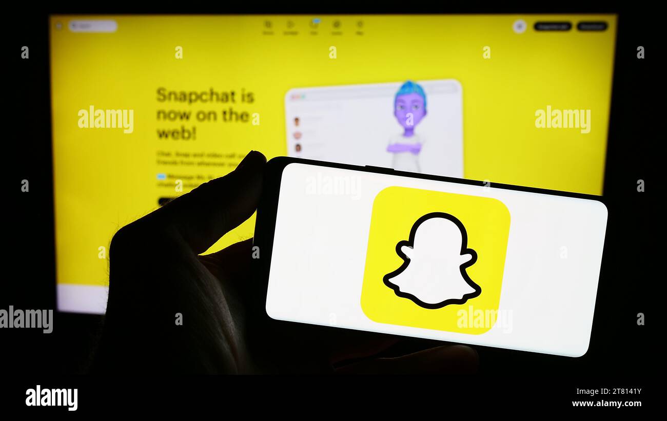 Personne tenant le smartphone avec le logo de l'application de messagerie instantanée multimédia américaine Snapchat en face du site Web. Concentrez-vous sur l'affichage du téléphone. Banque D'Images