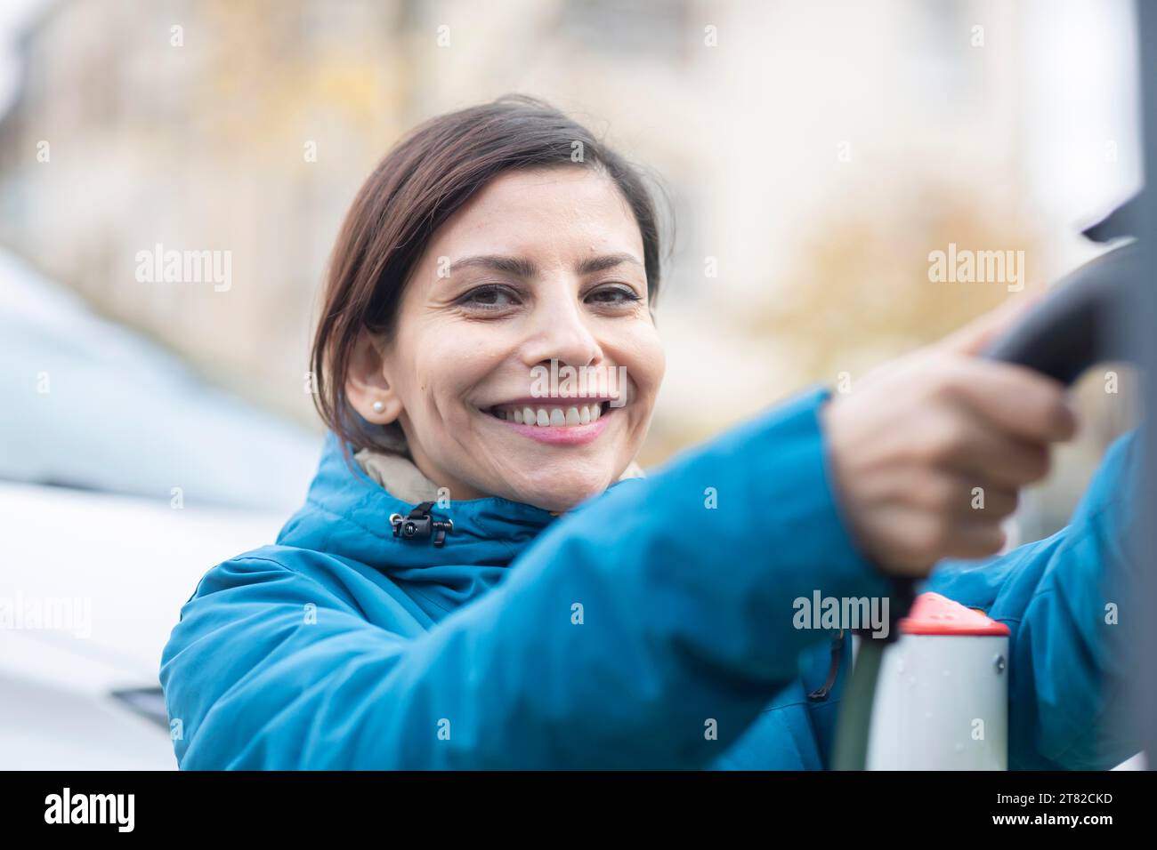 Femme charge une voiture électrique à une borne de recharge électrique Banque D'Images