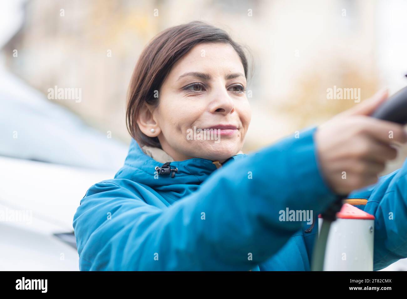 Femme charge une voiture électrique à une borne de recharge électrique Banque D'Images