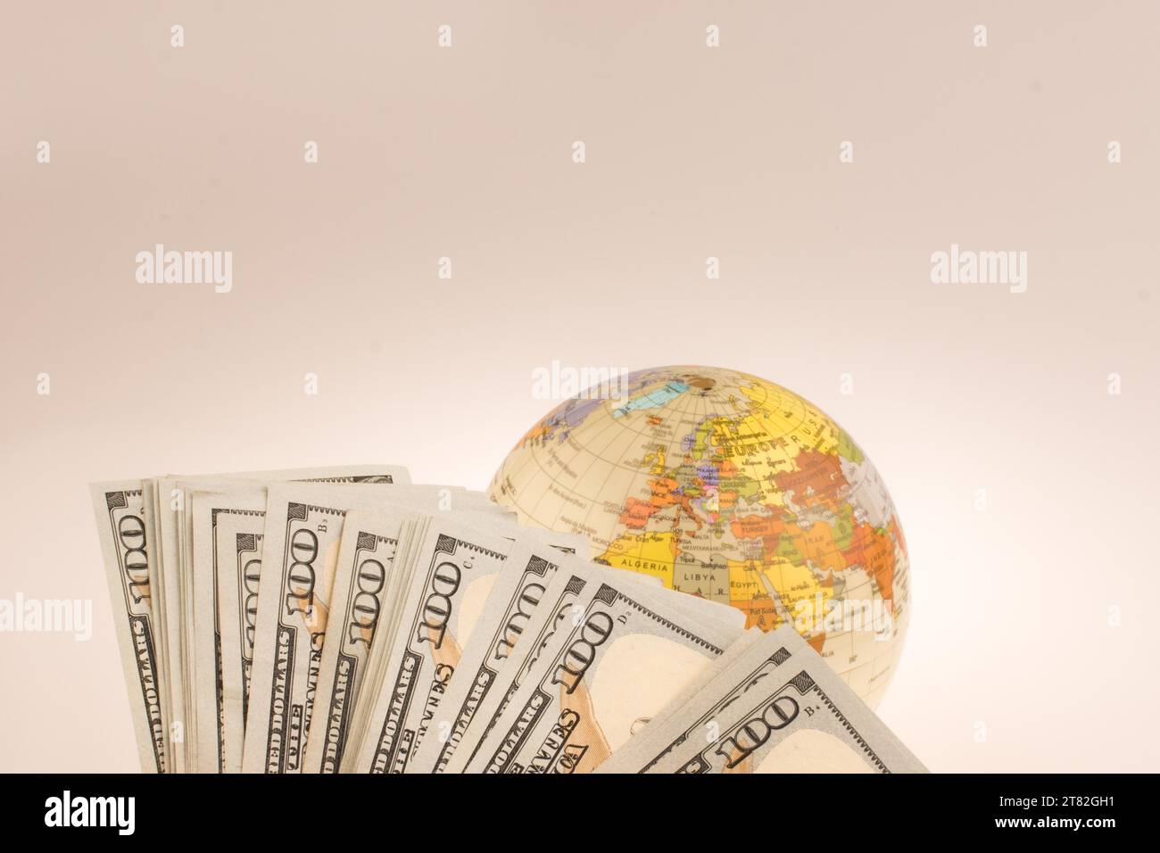 Human hand holding American dollar billets par le côté d'un modèle globe on white background Banque D'Images