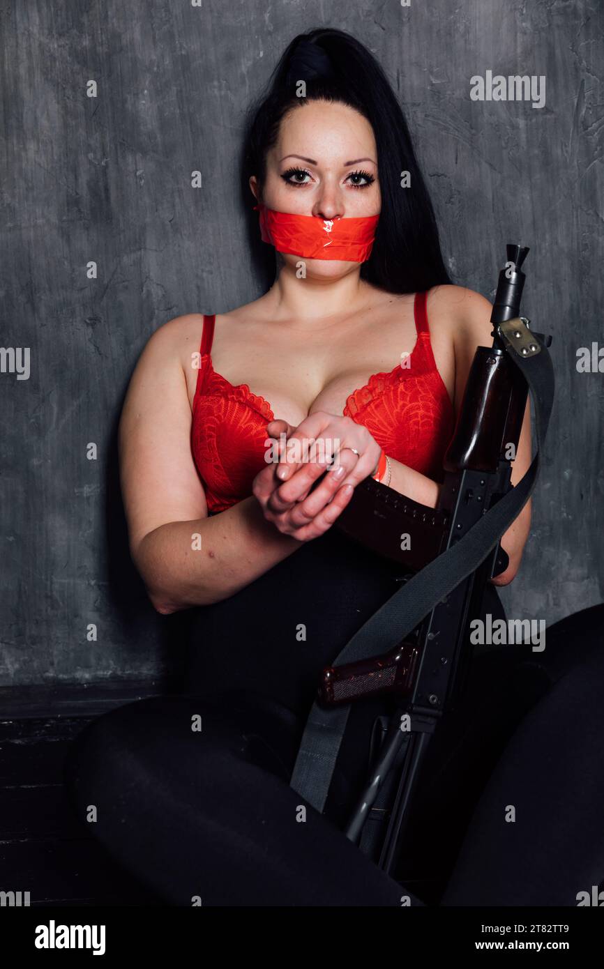 femme brunette dans une pièce sombre avec une mitrailleuse Banque D'Images