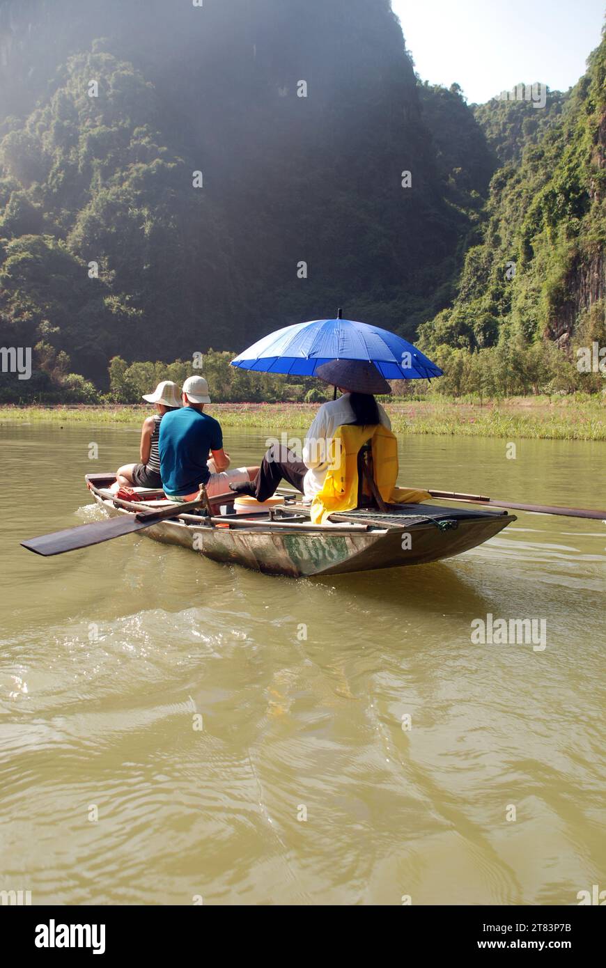 Les touristes montent dans des bateaux à rames vietnamiens traditionnels parmi les falaises de calcaire et les grottes de Tam COC Banque D'Images