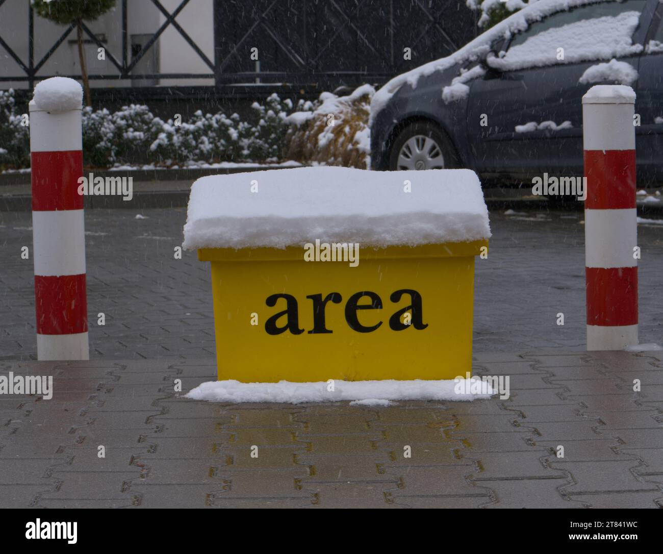 Une boîte jaune de sable recouverte de neige entre les poteaux de stationnement Banque D'Images