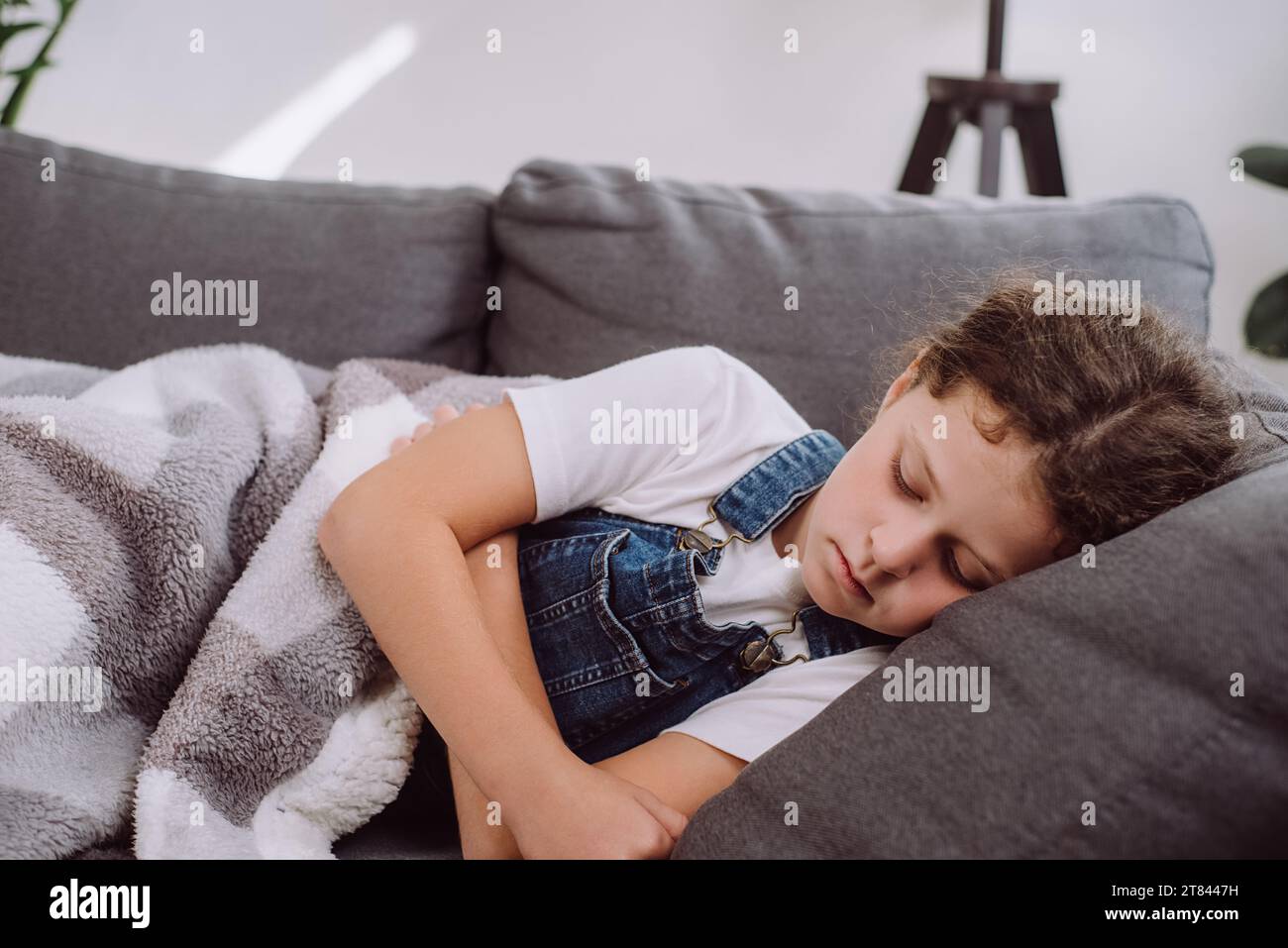 Gros plan d'une fille préadolescente malade et malsaine couchée seule sur un canapé sous une couverture dans le salon à la maison. Mal bouleversé enfant caucasien a de la fièvre. Concept de guérison Banque D'Images