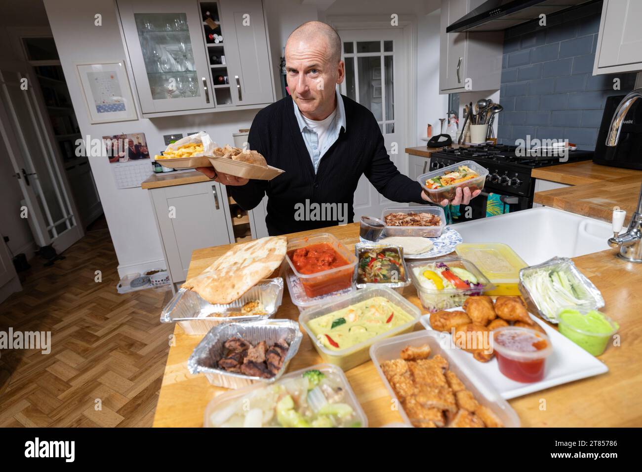 Homme à la maison avec section de plats à emporter sur son plan de travail de cuisine, Londres, Angleterre, Royaume-Uni Banque D'Images