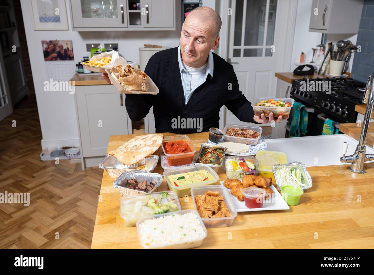 Homme à la maison avec section de plats à emporter sur son plan de travail de cuisine, Londres, Angleterre, Royaume-Uni Banque D'Images