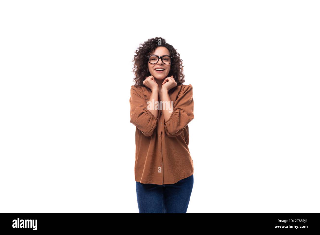 jeune agréablement surprise joyeuse femme mince avec une coupe de cheveux bouclés est habillée d'une chemise marron Banque D'Images