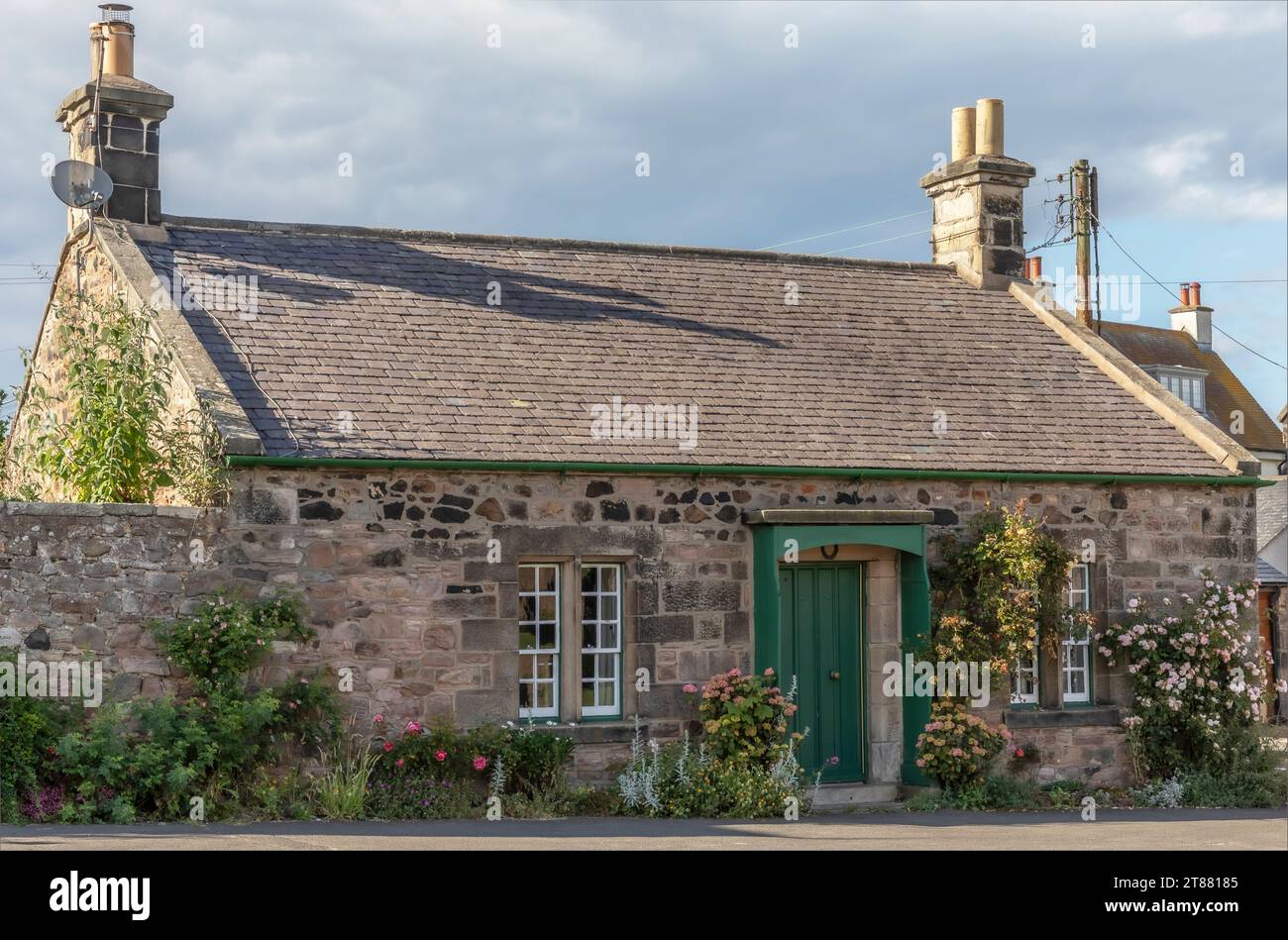 Cottage écossais avec des roses autour de la porte d'entrée abritée qui est peinte en vert Banque D'Images