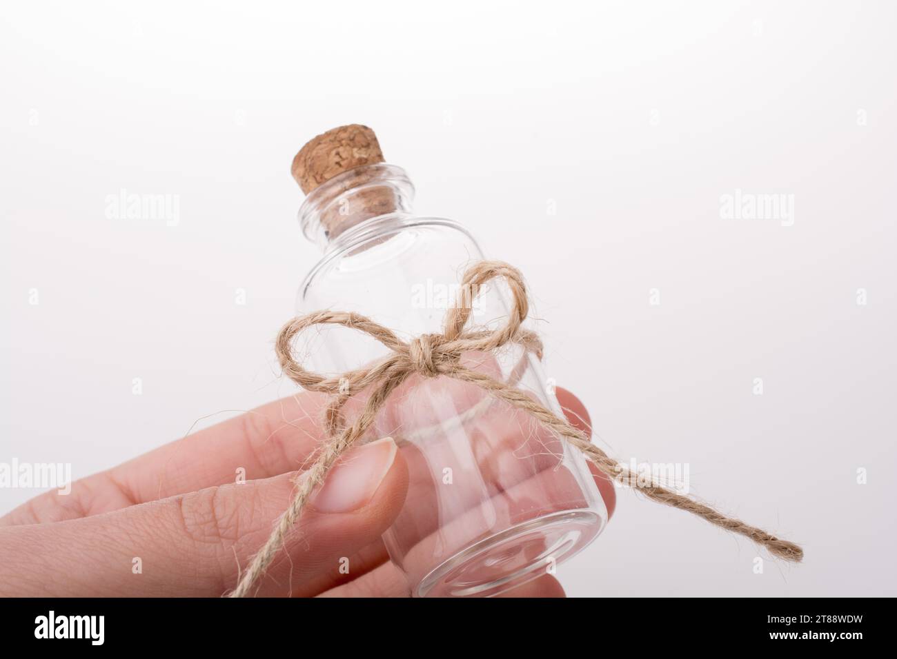 Petite bouteille en verre vide dans la main sur un fond blanc Banque D'Images