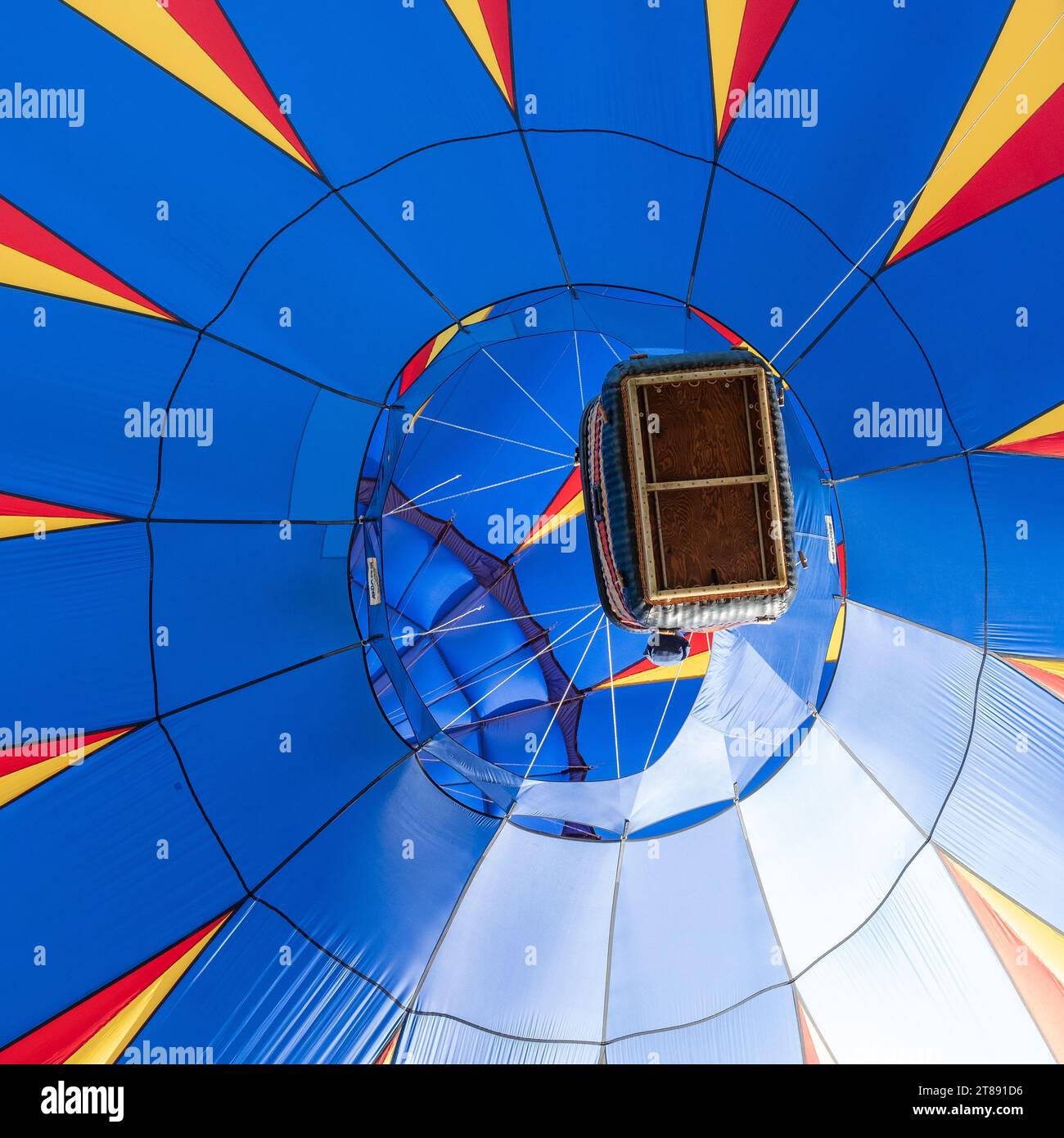 Regardant vers le haut une montgolfière bleue pendant qu’elle vole au-dessus, avec une vue dégagée sur l’enveloppe du ballon et sur le panier du pilote. Banque D'Images