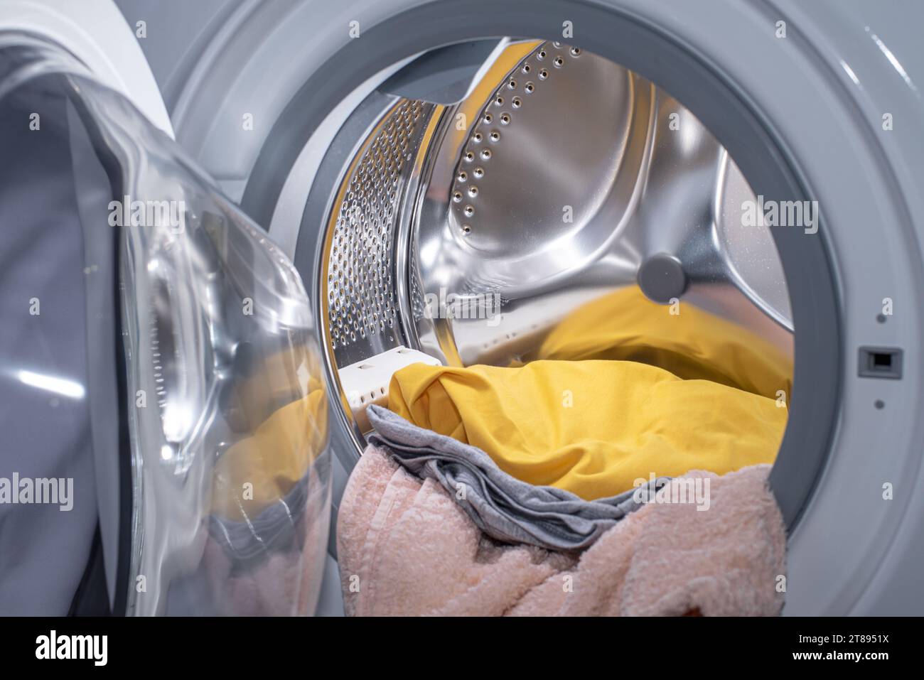Le tambour (réservoir) du lave-linge avant avec le linge à l'intérieur. Banque D'Images