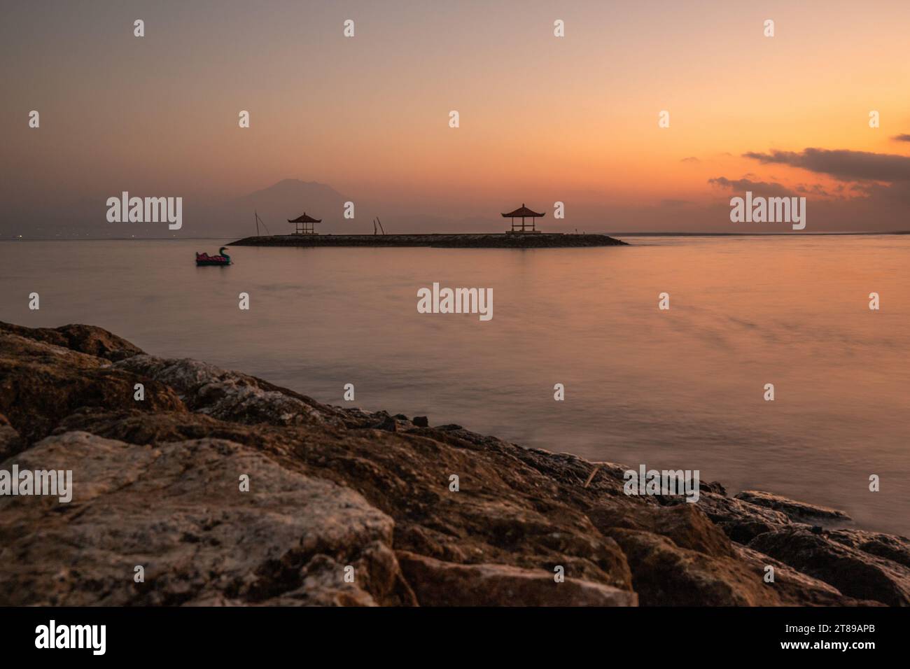 Plage de Sanur. Temple dans la mer calme. Petites vagues le matin. Plage de sable sur l'île de rêve de Bali. En arrière-plan le volcan Mont Agung Banque D'Images