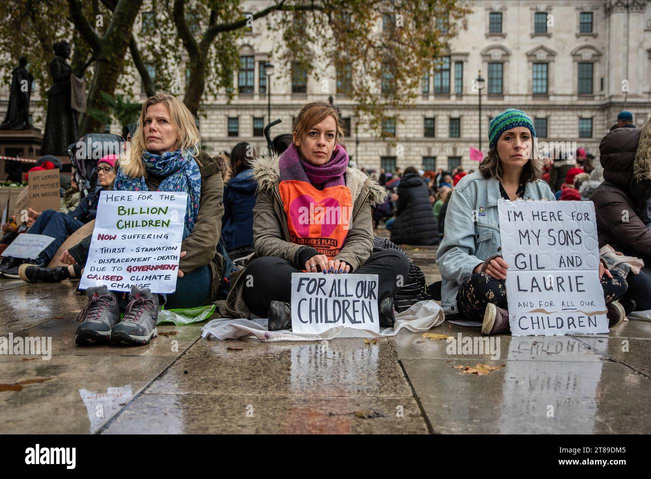 Londres, Royaume-Uni. 18 novembre 2023. Les manifestants tiennent des pancartes alors qu'ils sont assis sur le sol par temps pluvieux sur la place du Parlement. Mothers Rebellion a organisé une petite manifestation sur la place du Parlement à Londres, au Royaume-Uni. Crédit : SOPA Images Limited/Alamy Live News Banque D'Images