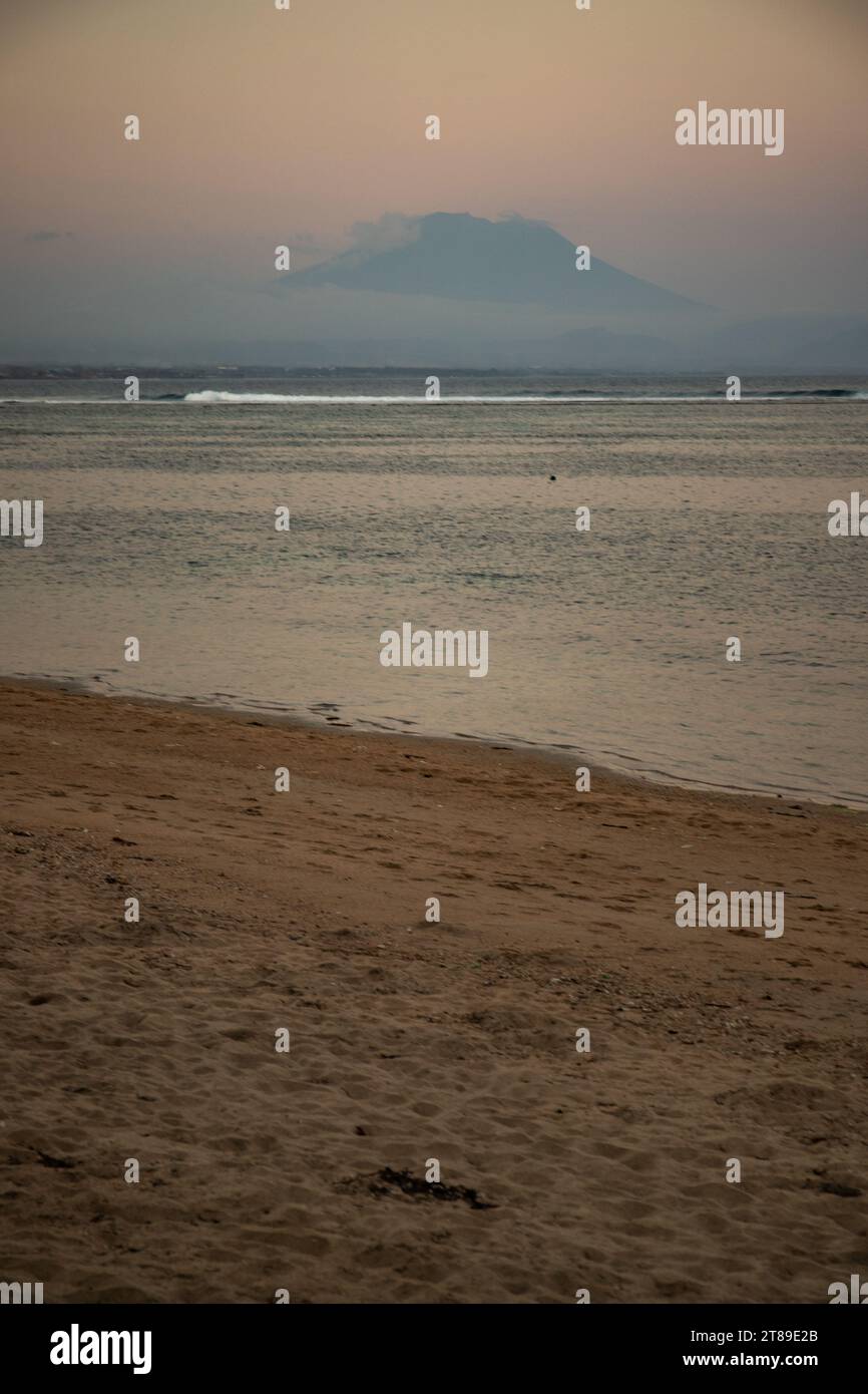 Plage de Sanur. Temple dans la mer calme. Petites vagues le matin. Plage de sable sur l'île de rêve de Bali. En arrière-plan le volcan Mont Agung Banque D'Images