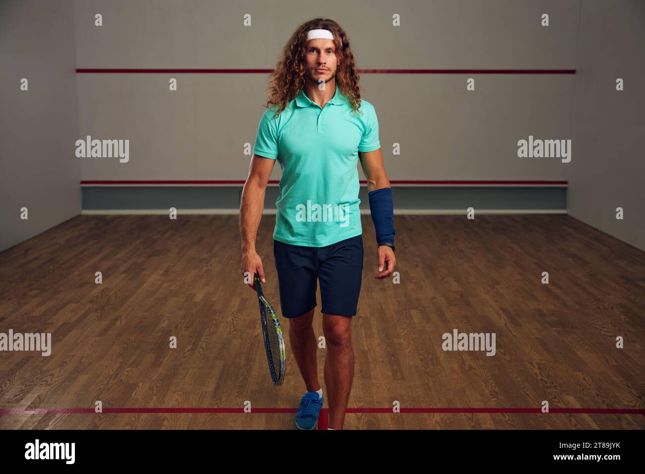 Portrait d'un homme tenant une raquette de squash marchant parmi un terrain de sport Banque D'Images
