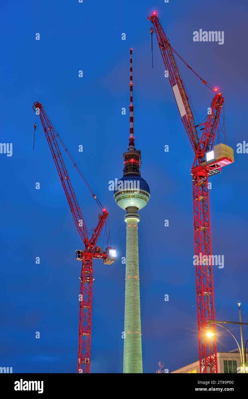 La célèbre tour de télévision de Berlin la nuit avec deux grues de construction rouges Banque D'Images