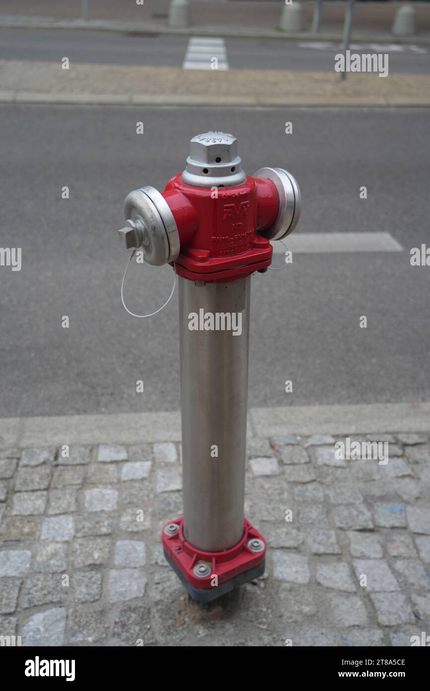 Tuyau d'eau de prise d'eau de ville rouge isolé unique avec rue en arrière-plan, tuyau métallique, approvisionnement en eau, fauget, vanne de tuyau d'urgence Banque D'Images