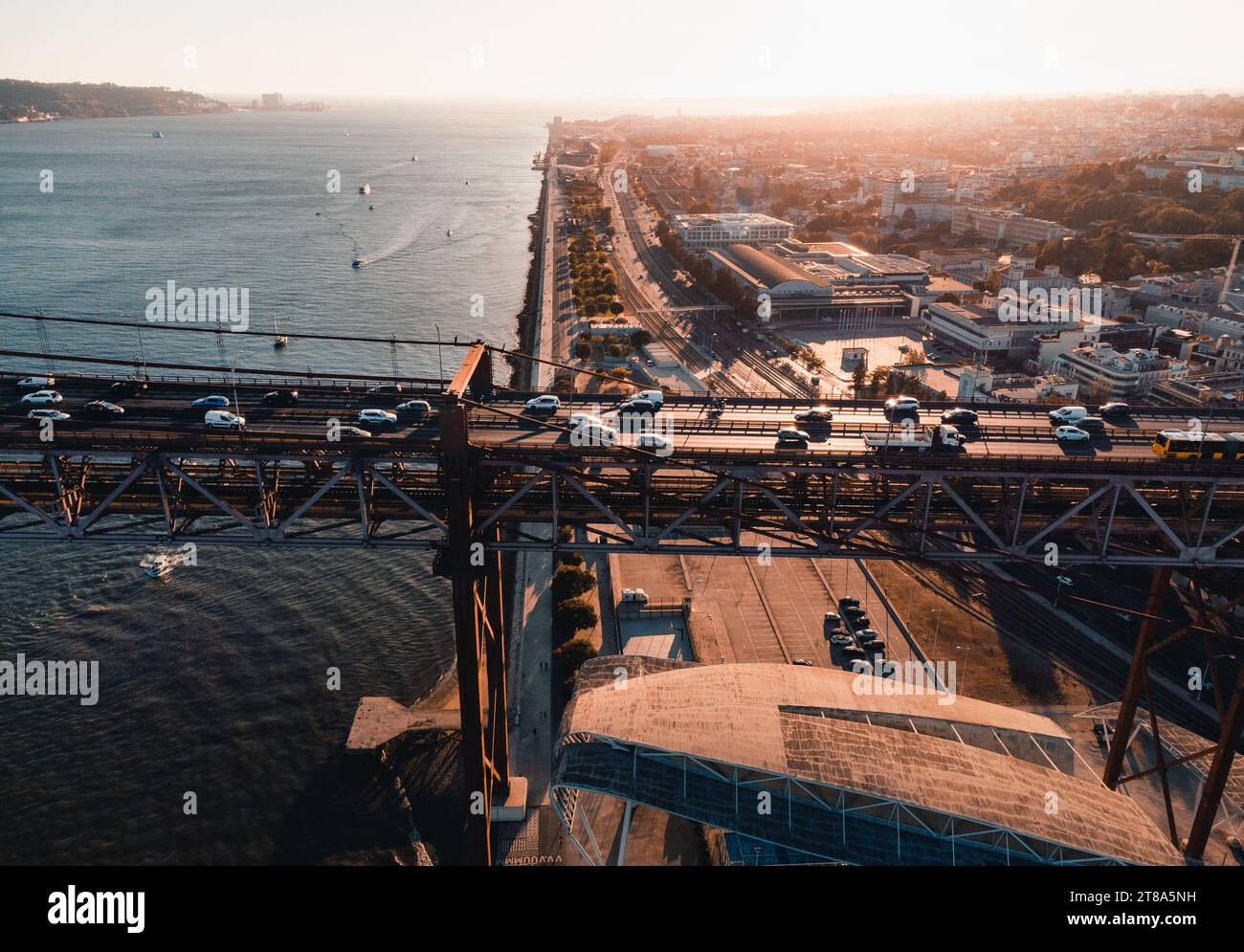 Photo horizontale aérienne des rues et des bâtiments de Lisbonne au coucher du soleil. Le pont du 25 avril à Libson avec port et fleuve Tage d'en haut sur golde Banque D'Images