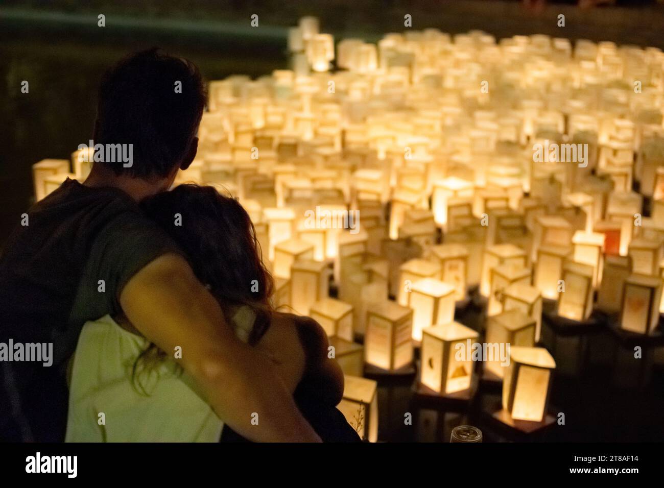 Embrassant un couple contemplant des lanternes de papier sur l'eau comme événement asiatique en soirée Banque D'Images