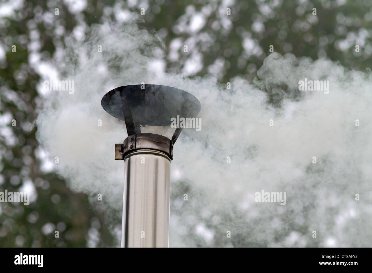de la fumée chaude s'échappe d'un tuyau en étain sur fond d'arbres d'automne Banque D'Images