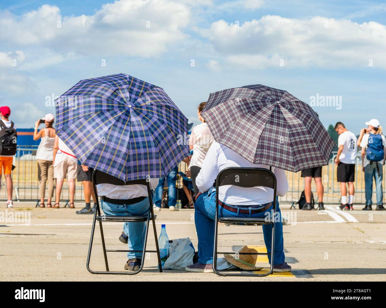 Deux hommes avec des parasols assis sur des chaises au soleil. Concept de chaleur estivale. Banque D'Images