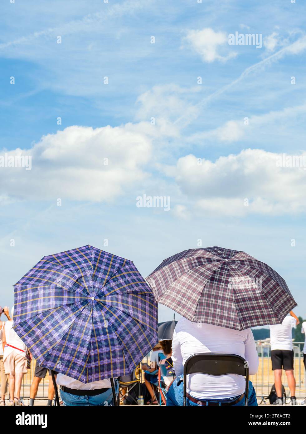 Deux hommes avec des parasols assis sur des chaises au soleil. Concept de chaleur estivale. Banque D'Images