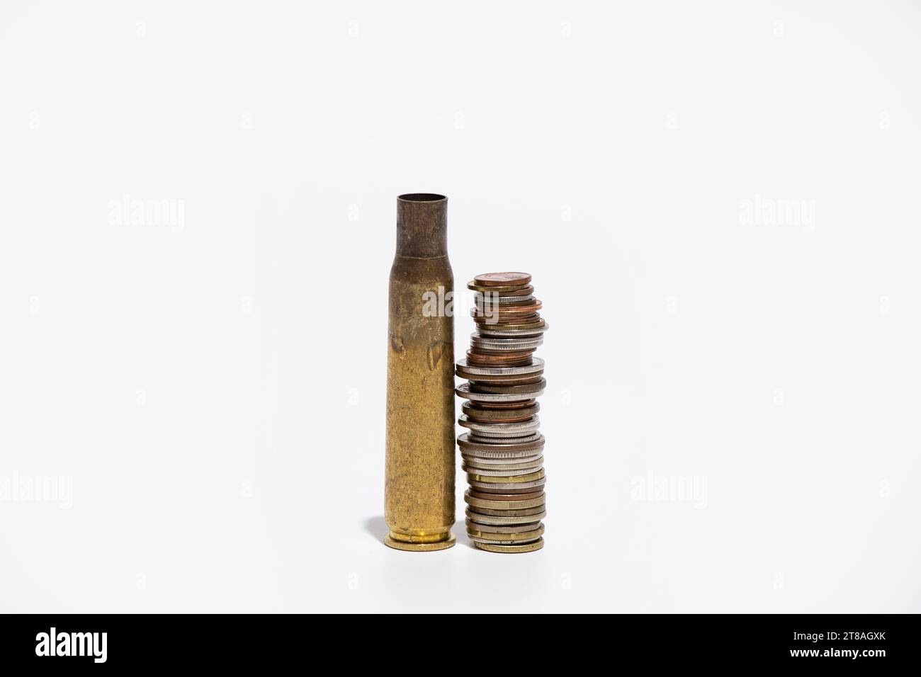 Cartouches de mitrailleuses vides et une pile de pièces de monnaie sur fond blanc, munitions et armes et affaires, argent pour armes pour l'Ukraine Banque D'Images