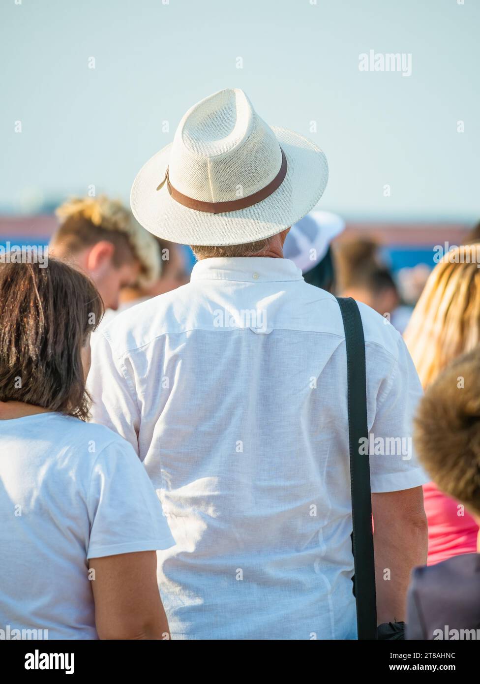 Photo de vue arrière d'un homme portant un élégant chapeau entouré par une foule de gens. Banque D'Images