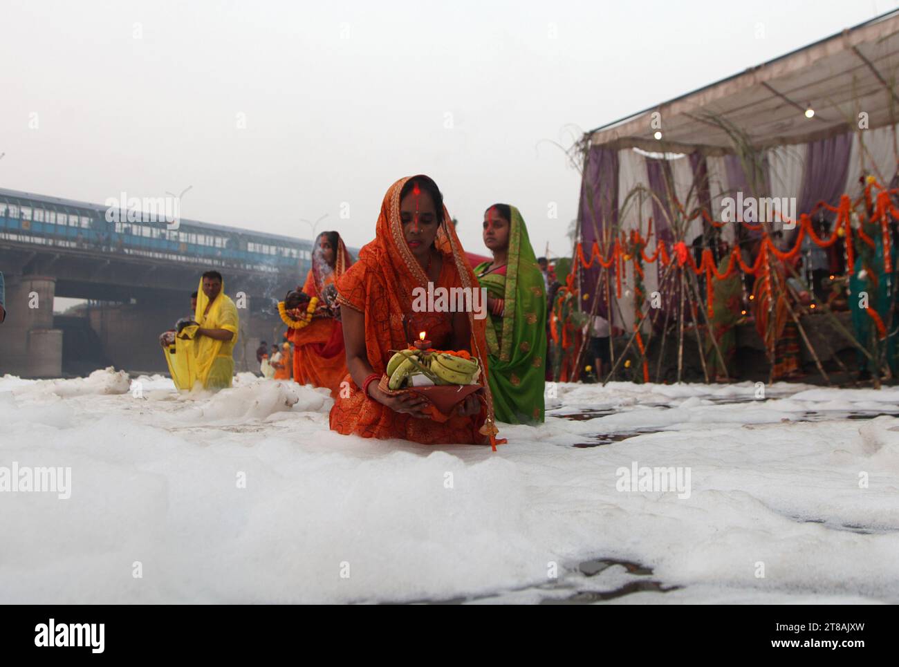 Noida, Inde. 19 novembre 2023, les dévots hindous se réunissent pour accomplir des rituels au dieu Soleil alors qu’ils se tiennent au milieu des eaux polluées de la rivière Yamuna recouverte d’une couche de mousse toxique, à l’occasion du festival Chhath Puja à Noida, dans la banlieue de New Delhi, en Inde. Crédit : Anil Shakya/Alamy Live News Banque D'Images