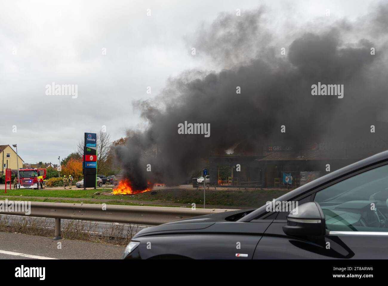 Feering, Colchester, Essex, Royaume-Uni. 19 novembre 2023. Une voiture en feu près de l'A12 Arterial Road près de Colchester devant un arrêt Greggs et Burger King, et près d'une station-service Esso. La circulation est ralentie au passage. Rapport d'incident : cause de l'incendie : surchauffe, cause inconnue. Source d'allumage : véhicule uniquement - moteur, conduite de carburant ou pompe Banque D'Images