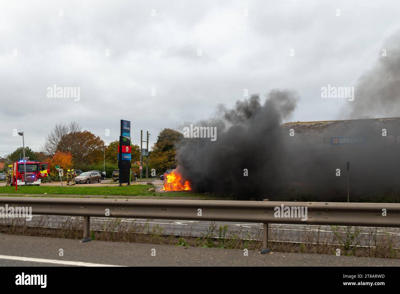 Feering, Colchester, Essex, Royaume-Uni. 19 novembre 2023. Une voiture en feu près de l'A12 Arterial Road près de Colchester devant un arrêt Greggs et Burger King, et près d'une station-service Esso. La circulation est ralentie au passage. Rapport d'incident : cause de l'incendie : surchauffe, cause inconnue. Source d'allumage : véhicule uniquement - moteur, conduite de carburant ou pompe Banque D'Images