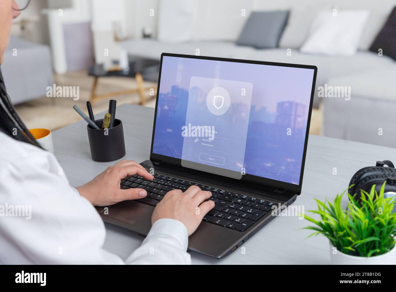 Femme travaillant sur un ordinateur portable, avec un formulaire de connexion de sécurité planant au-dessus. Fusionnez la productivité avec l'assurance de la sécurité numérique Banque D'Images