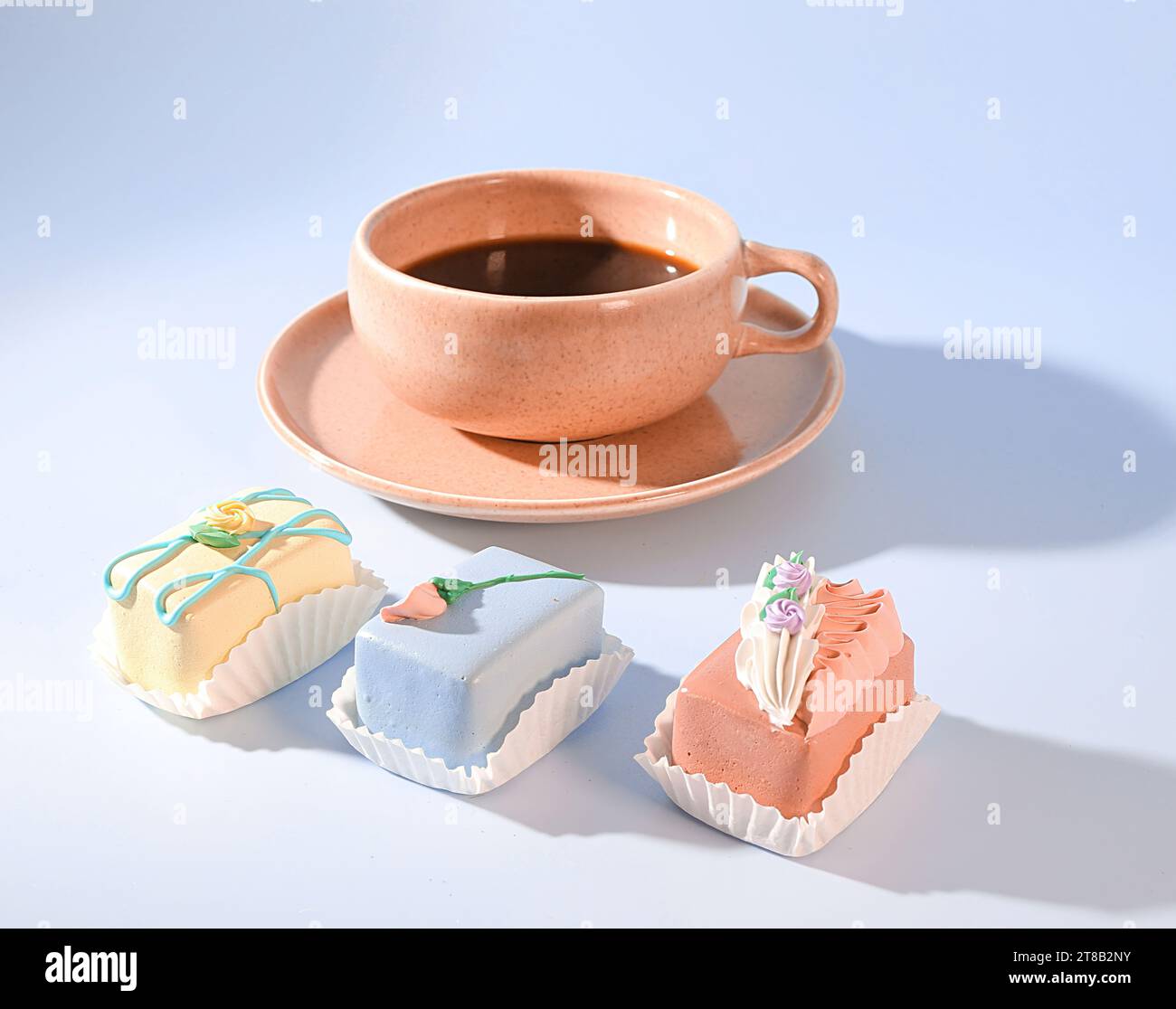 Un paradis pastel de douceur : un espresso rose et un Selection Pretty, Mini Bakery Cakes Banque D'Images