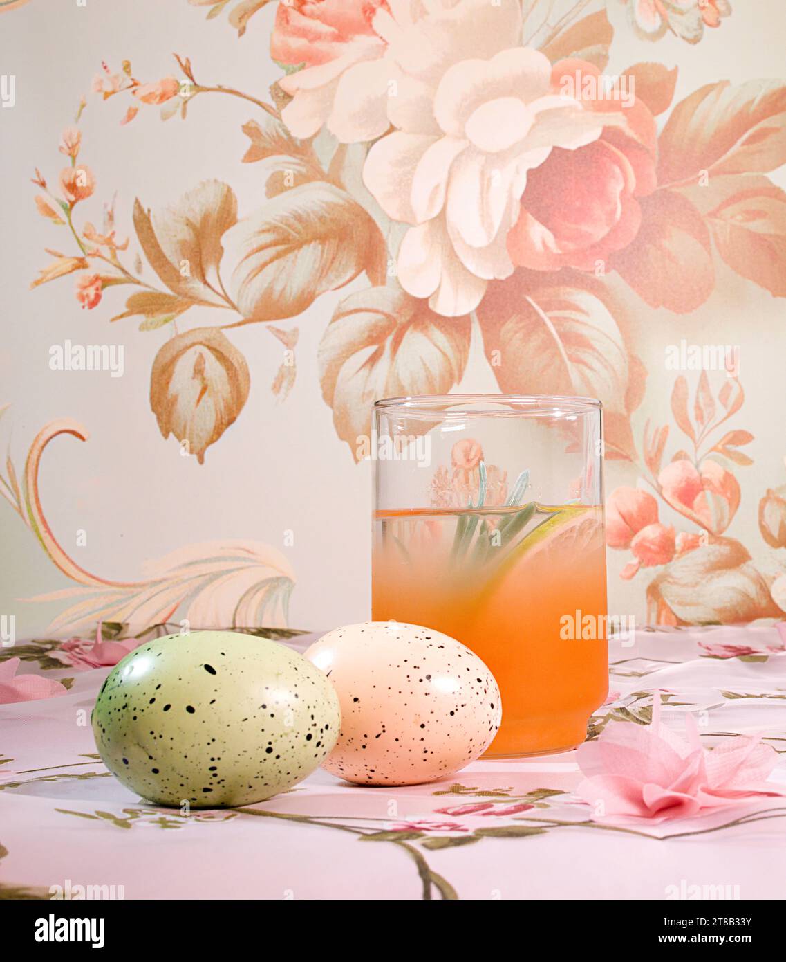 Un tableau de romance et de nostalgie : un cocktail d'agrumes et des œufs de Pâques pastel dans un cadre floral Cottage Core délicat Banque D'Images