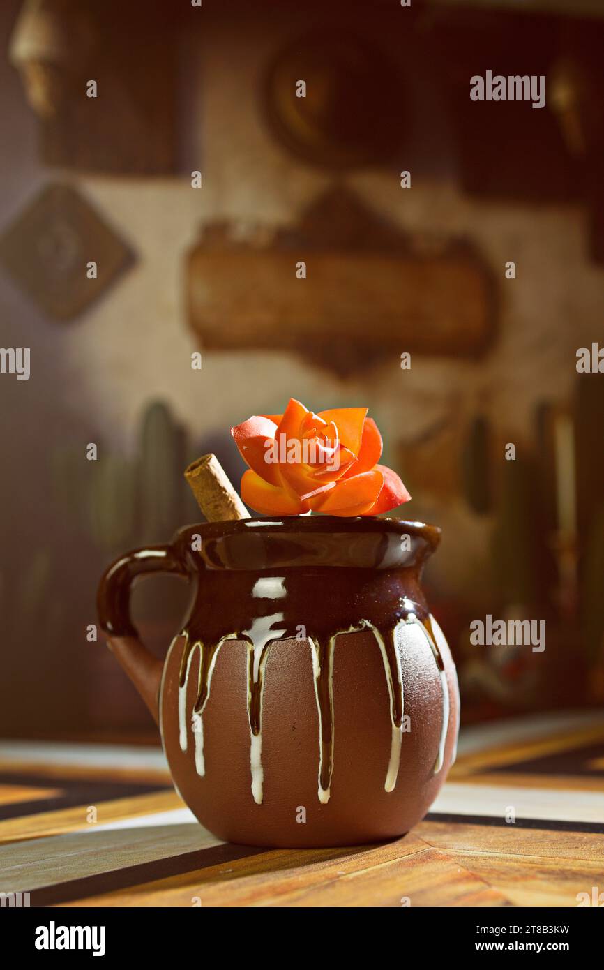 Mug mexicain Champurrado chocolat chaud en argile rustique traditionnelle Jarritos avec bâton de cannelle Banque D'Images