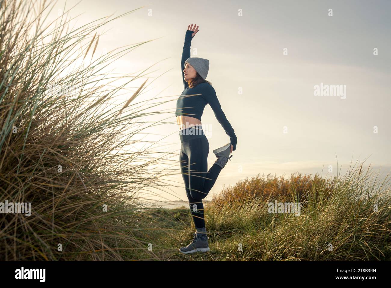 Femme sportive étirant ses jambes, faisant debout quadriceps étirement de la cuisse avant avant de courir l'entraînement le matin, Banque D'Images
