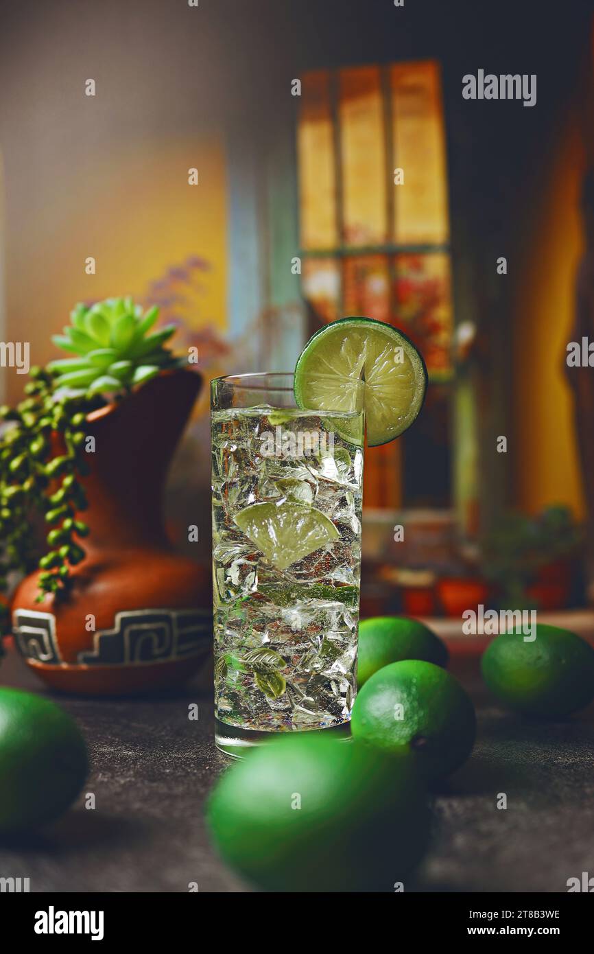 Cocktail Mojito dans un grand verre et citron vert associé à un carafe en argile mexicaine traditionnelle à l'intérieur d'un comptoir de cuisine rustique Banque D'Images