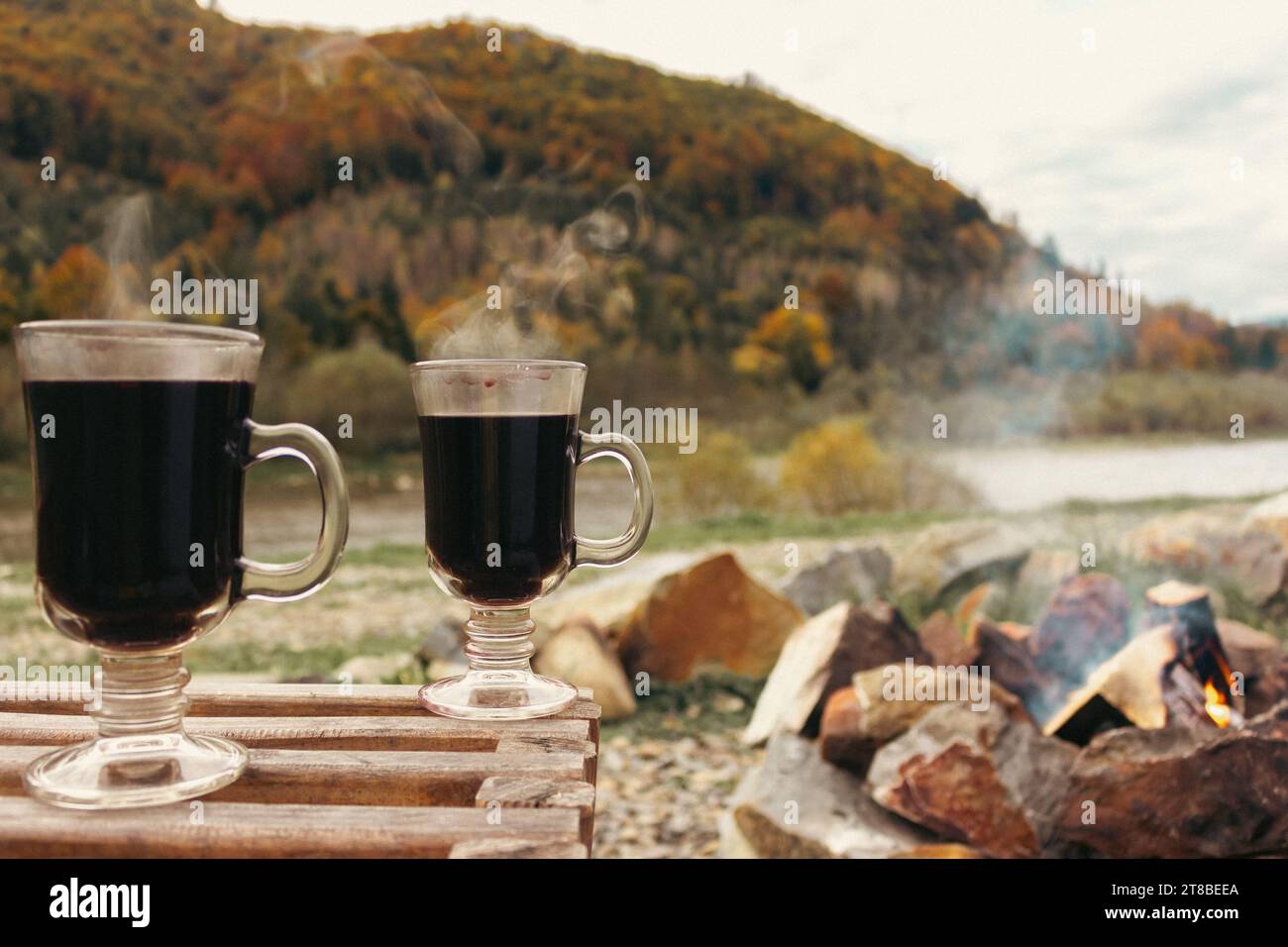 Deux verres avec du vin rouge chaud sur fond de montagnes d'automne. Pique-nique avec boissons alcoolisées et feu de camp. Vacances pour deux. Vin chaud dans la zone de pique-nique. Banque D'Images
