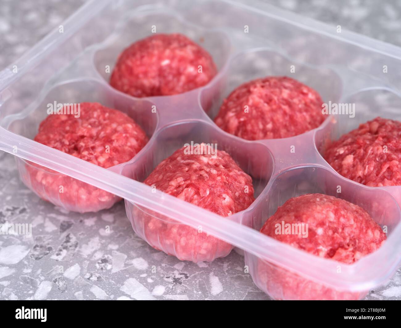 Patties de bœuf crues dans un récipient en plastique. Gros plan. Banque D'Images