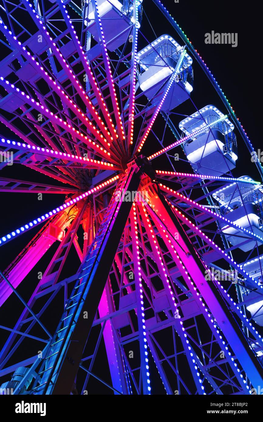 Ferris roue également connue sous le nom de roue d'observation géante, promenade divertissante populaire dans le parc d'attractions, vue à faible angle de scène de nuit avec mise au point sélective Banque D'Images