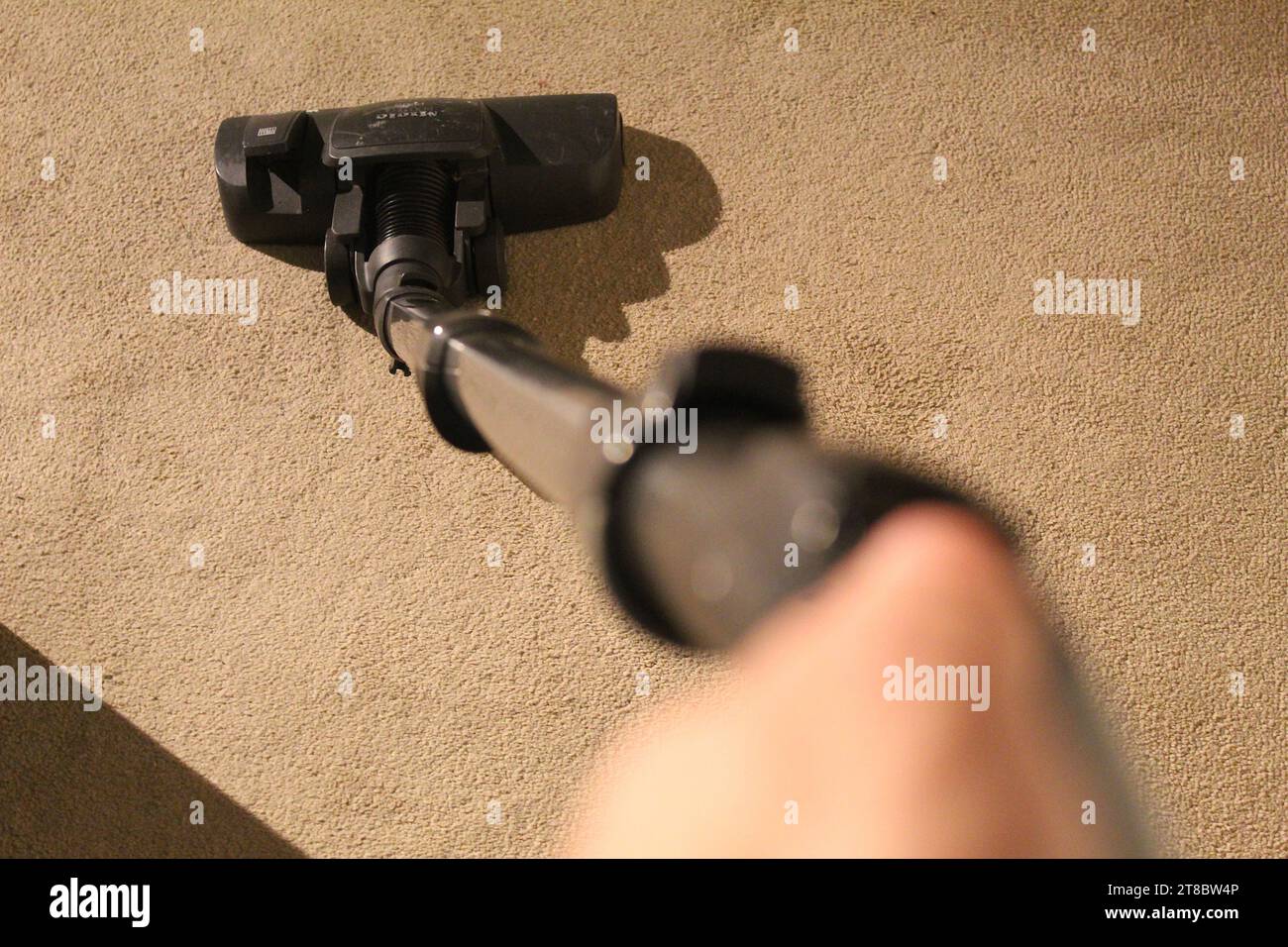 Une photo POV de quelqu'un tenant le hoover tout en enlacant un tapis. Banque D'Images