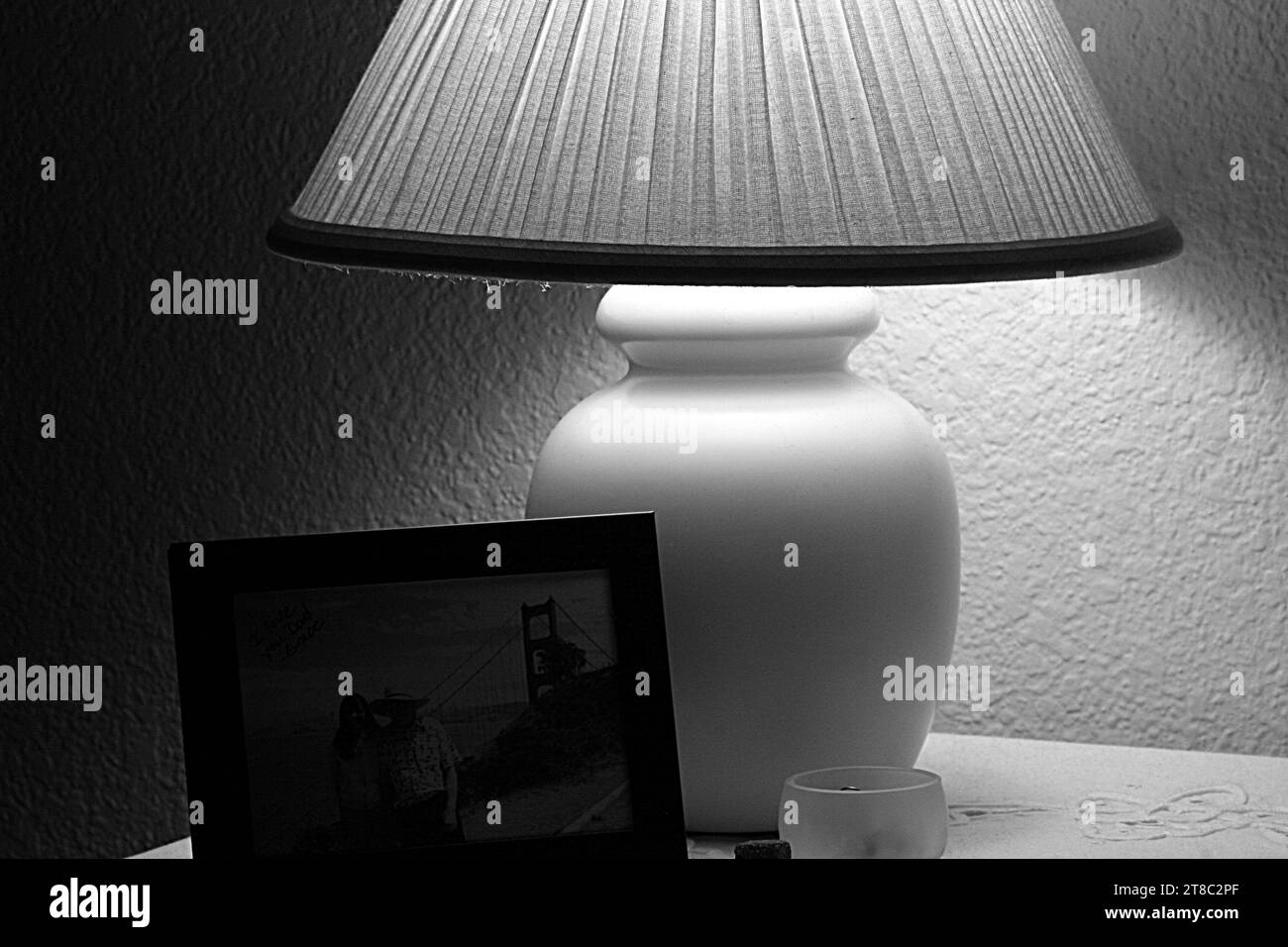 Image noir et blanc de la lampe et photo sur la table de nuit éclairée par la lumière douce de la lampe Banque D'Images
