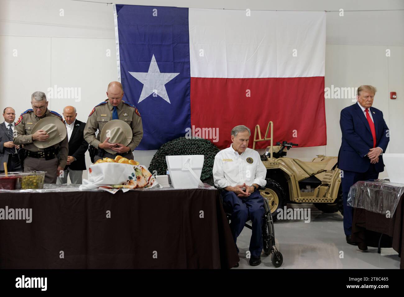 Edinburg, Texas États-Unis, novembre 19 2023:.l'ancien président DONALD TRUMP, candidat à l'investiture présidentielle républicaine, et le gouverneur du Texas GREG ABBOTT (au centre) inclinent la tête lors d'une prière pré-repas à l'aéroport international du Texas du Sud. Trump et Abbott ont servi des repas aux soldats de la Garde nationale du Texas et du Texas DPS qui sont stationnés à la frontière entre les États-Unis et le Mexique pendant les vacances de Thanksgiving. Photo de Michael Gonzalez/Pool Banque D'Images